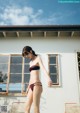 A woman in a bikini standing in front of a building.