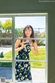 A woman standing in front of a window holding a camera.